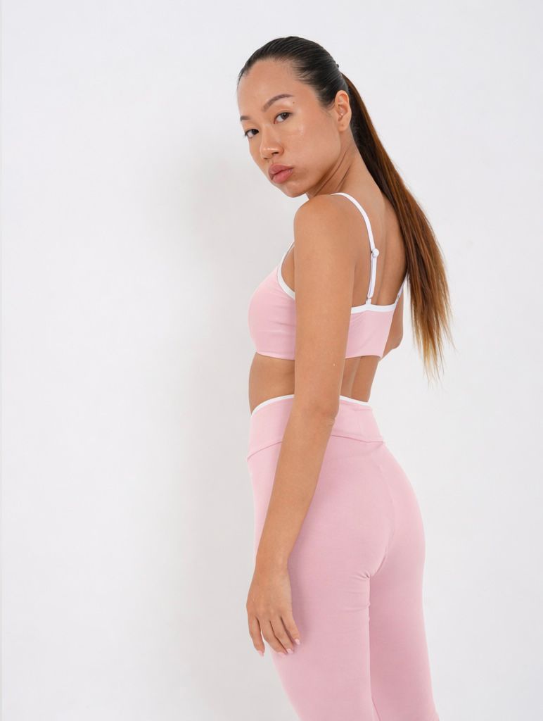 Woman wearing a pink sports bra and leggings back pose