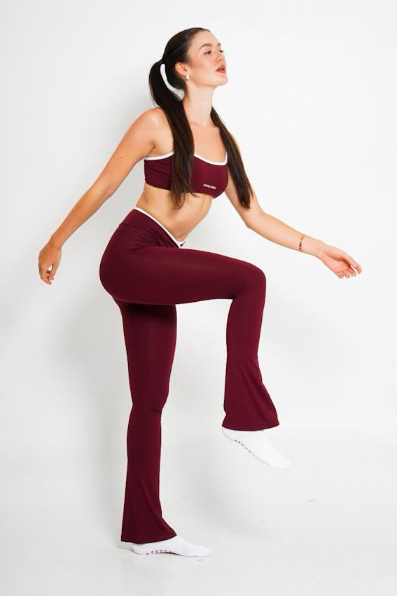 Woman in burgundy athletic wear posing against a white background