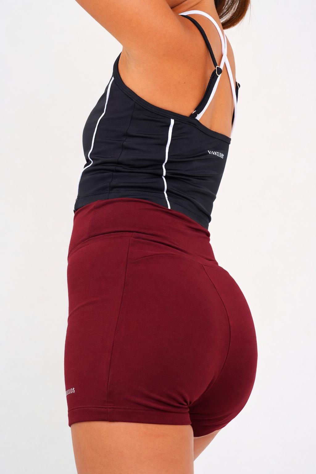 girl wearing a black tank top and maroon shorts 