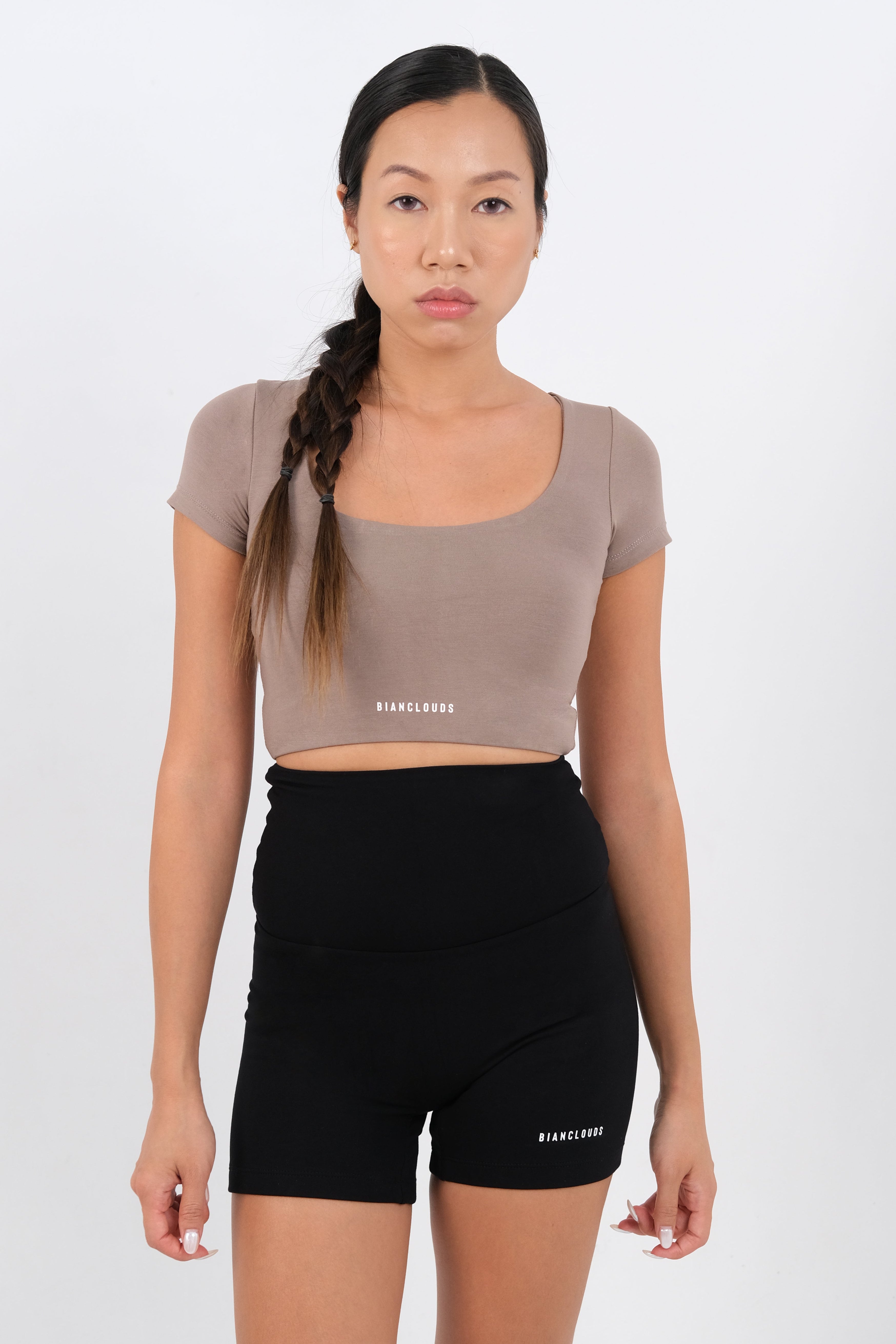 Woman wearing a beige crop top and black stretchy shorts 