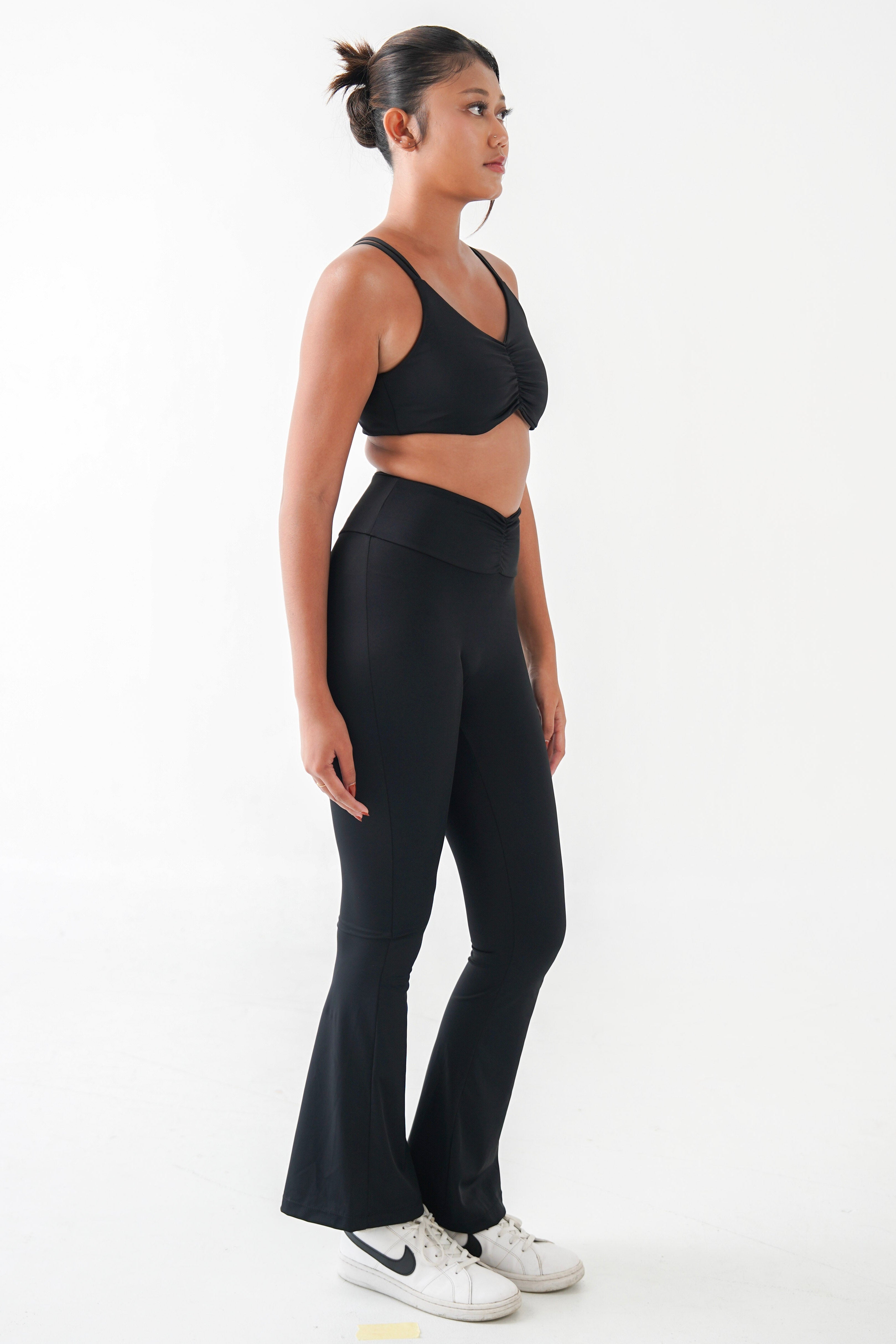 Woman wearing a black yoga pilates bra and flared pants