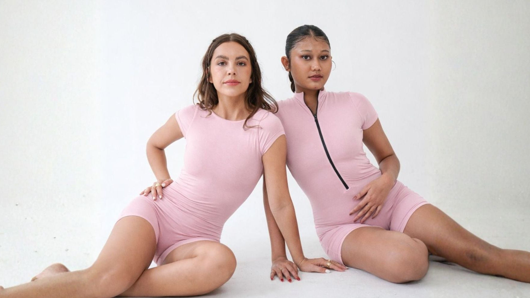 Two women wearing pink activewear yoga pilates bodysuits
